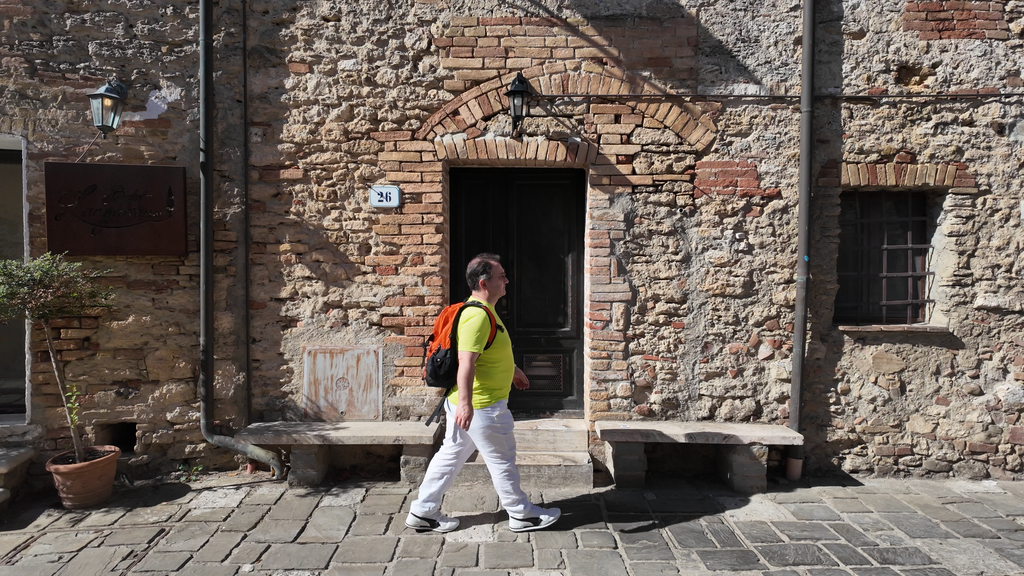 “Toscana autêntica: turista caminhando por uma antiga vila de pedra durante uma experiência de turismo na Itália, longe dos lugares viralizados nas redes sociais.”